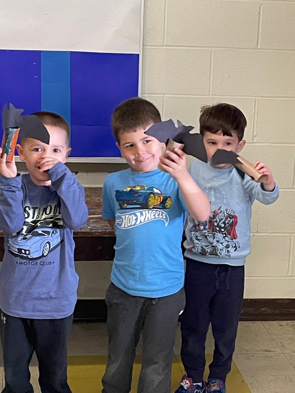 3 preschool boys holding paper bats for halloween